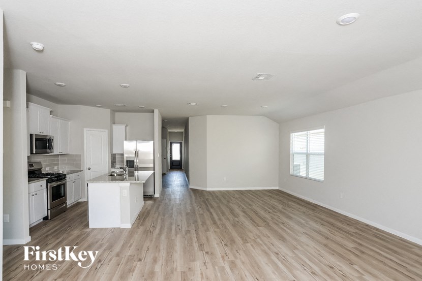 A spacious, empty room with wooden floors and white walls.