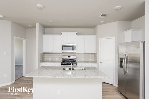 A kitchen with a stainless steel refrigerator and a granite countertop.