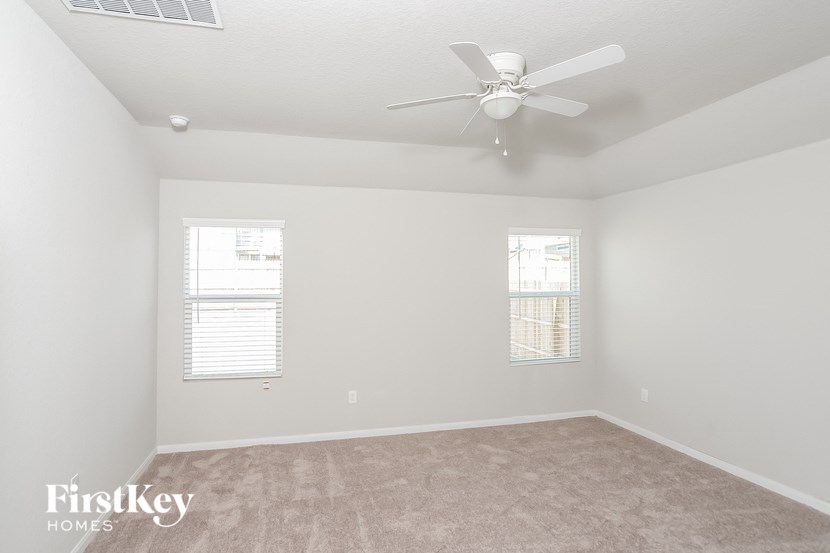 A room with a fan and two windows.