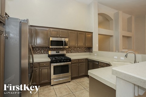 A kitchen with a refrigerator, stove, oven, and cabinets.