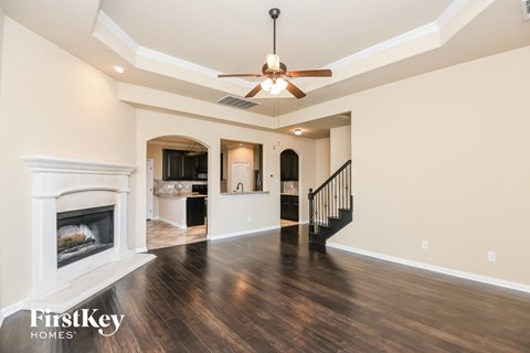 A spacious living room with a fireplace and a ceiling fan.
