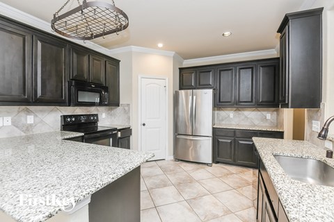 A kitchen with black cabinets and a granite countertop.