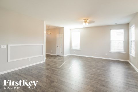 A spacious room with wooden flooring and white walls.