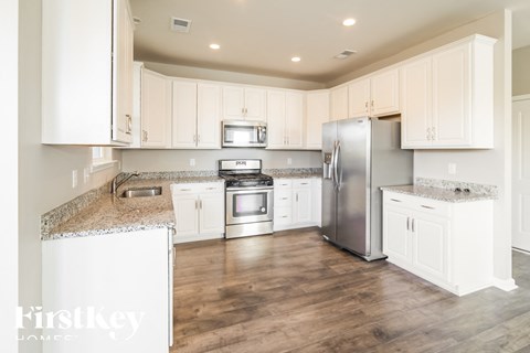 A kitchen with white cabinets and a granite countertop.