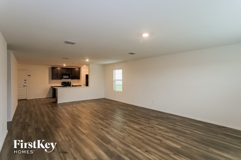 A spacious room with wooden flooring and a bar area in the corner.