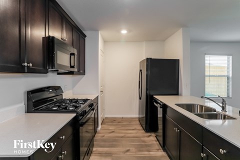 A kitchen with black cabinets and appliances is shown.