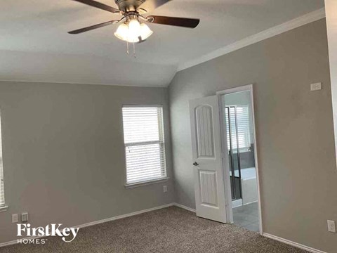 a bedroom with a ceiling fan and a door to the bathroom