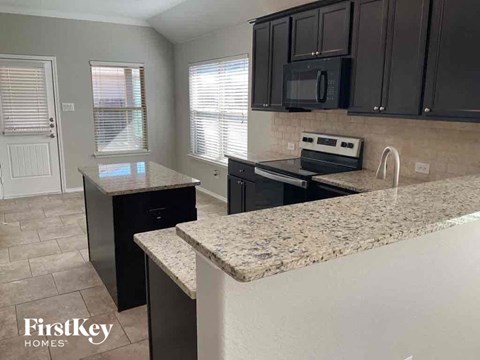 an updated kitchen with granite counter tops and black cabinets