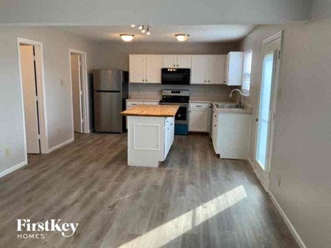 A kitchen with wooden floors and white cabinets.