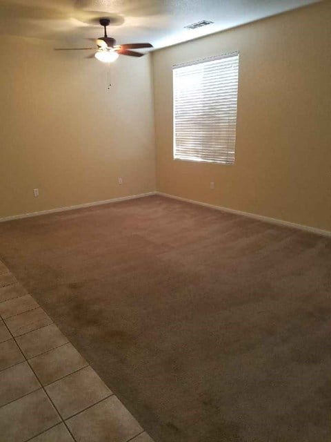 a living room with a carpet and a ceiling fan