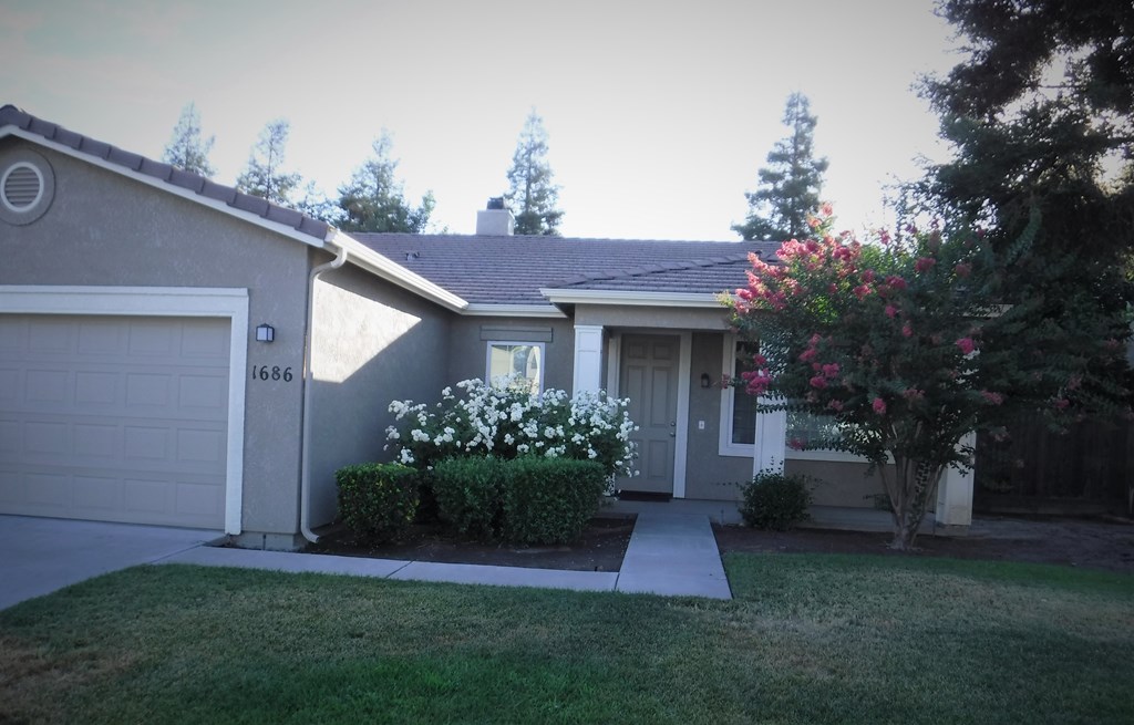 a gray house with a sidewalk in front of a yard