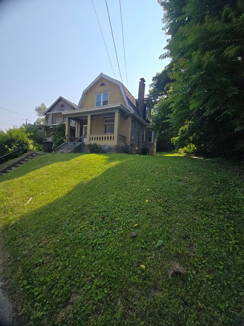 A house with a yellow front and a green lawn.