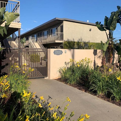 A building with the number 15020 on it is surrounded by plants and flowers.