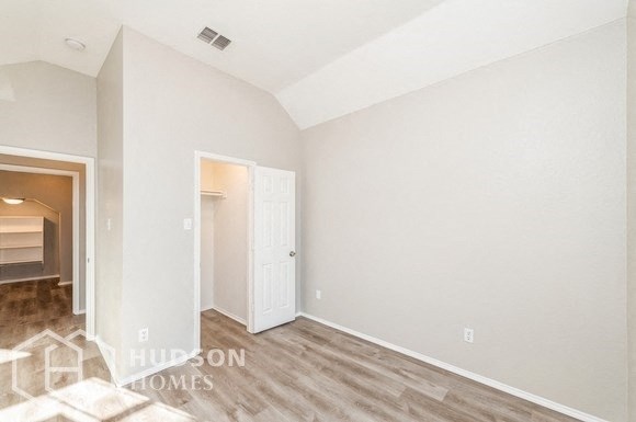 the spacious living room with wood flooring and white walls