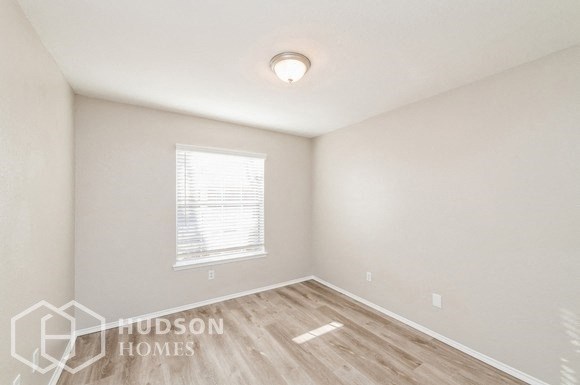 a bedroom with a wood floor and white walls and a window
