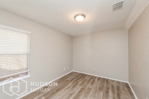 the spacious living room with wood flooring and a window