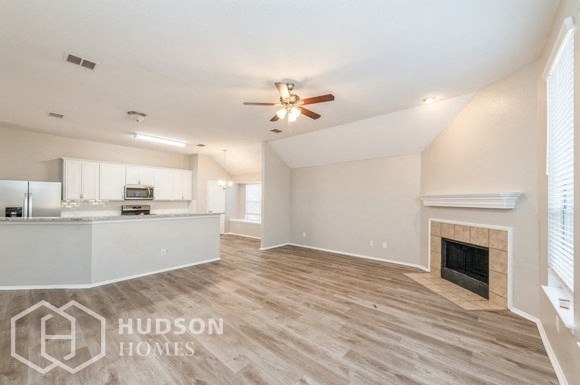 an open living room with a fireplace and a kitchen