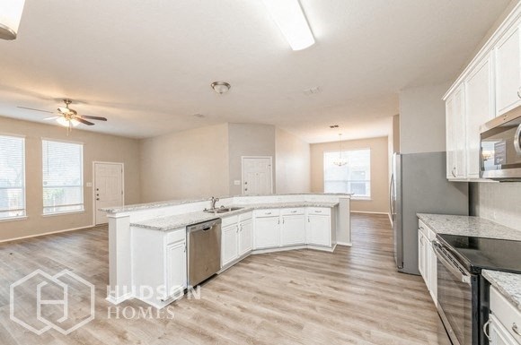 a large kitchen with white cabinets and a wood floor