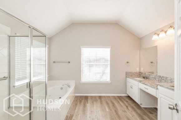 a white bathroom with a tub and a sink and a mirror