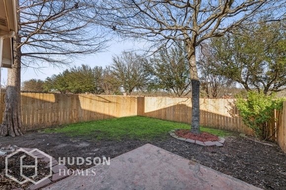 a backyard with a tree and a wooden fence