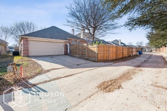 a house with a driveway and a fence in front of it