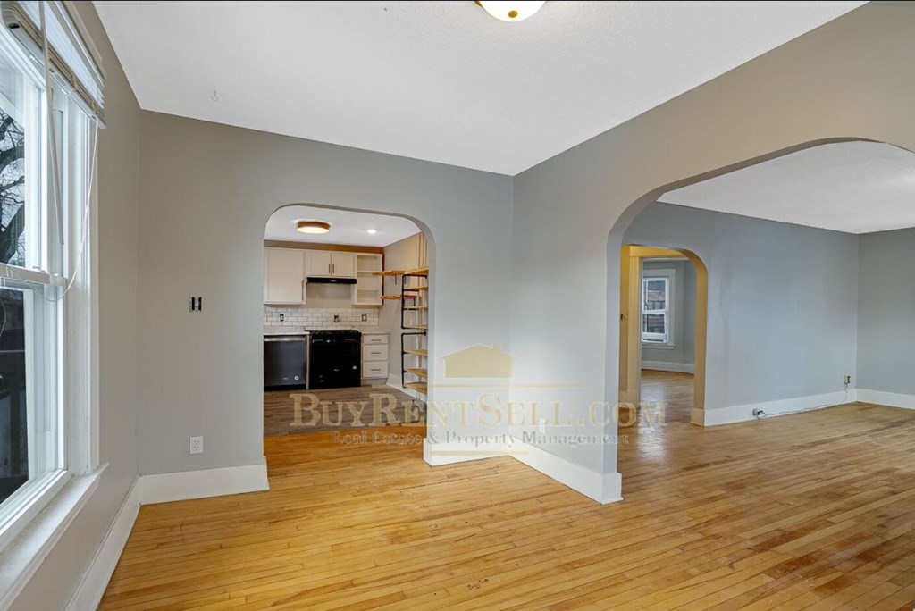 a renovated living room and kitchen with hardwood floors and white walls