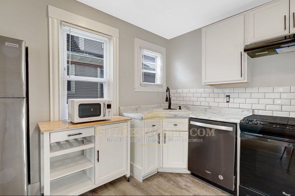 a small kitchen with white cabinets and a microwave