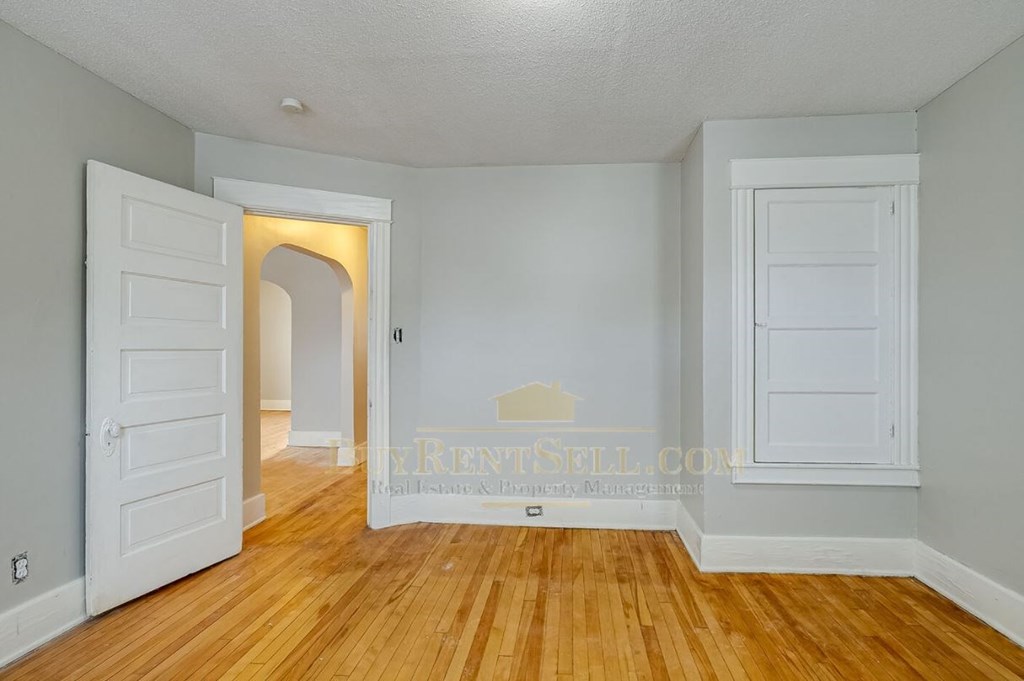an empty living room with white doors and wood floors