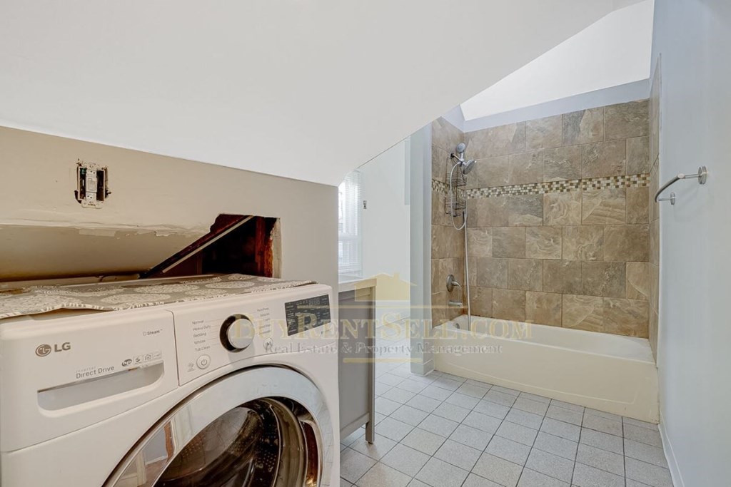 a washing machine in a bathroom with a shower and a tub