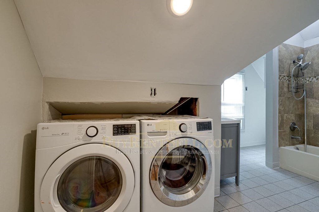 a washer and dryer in a bathroom with a shower and a sink