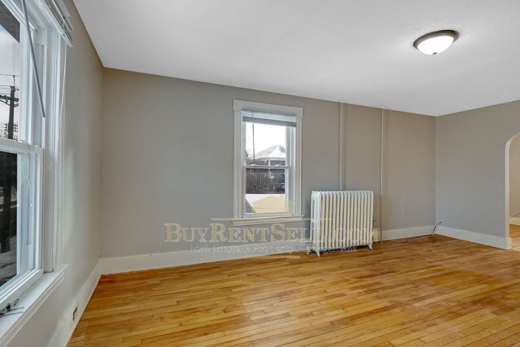 an empty living room with a wood floor and a window