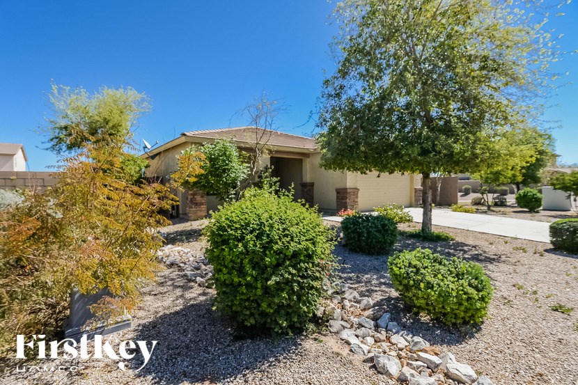 A house with a gravel driveway and a tree in front of it.