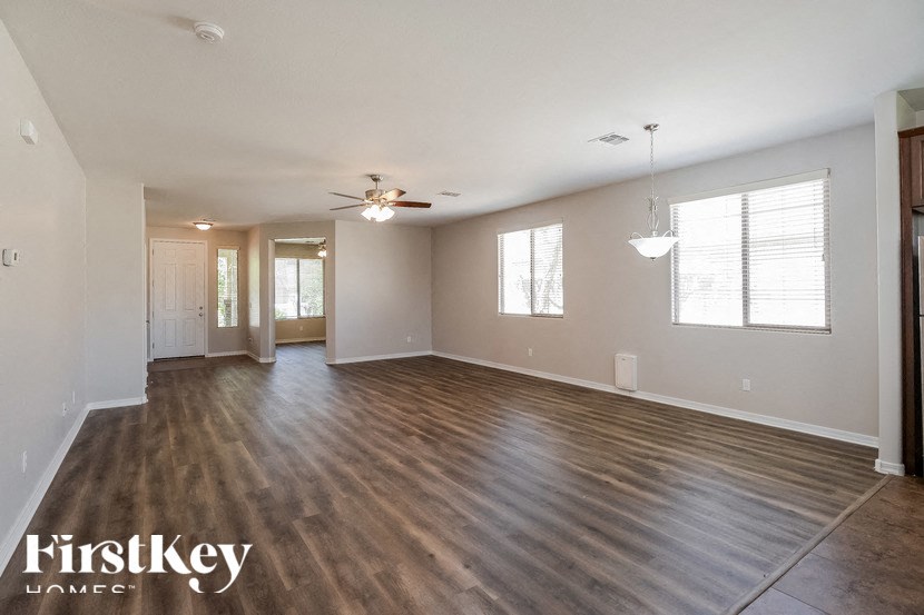 A spacious room with wooden flooring and a ceiling fan.