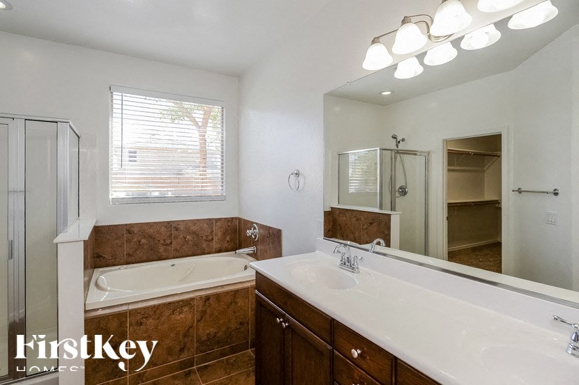 A bathroom with a tub, sink, and mirror.