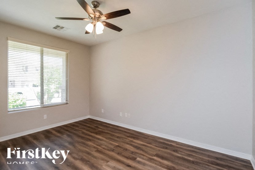 A room with a ceiling fan and wooden flooring.