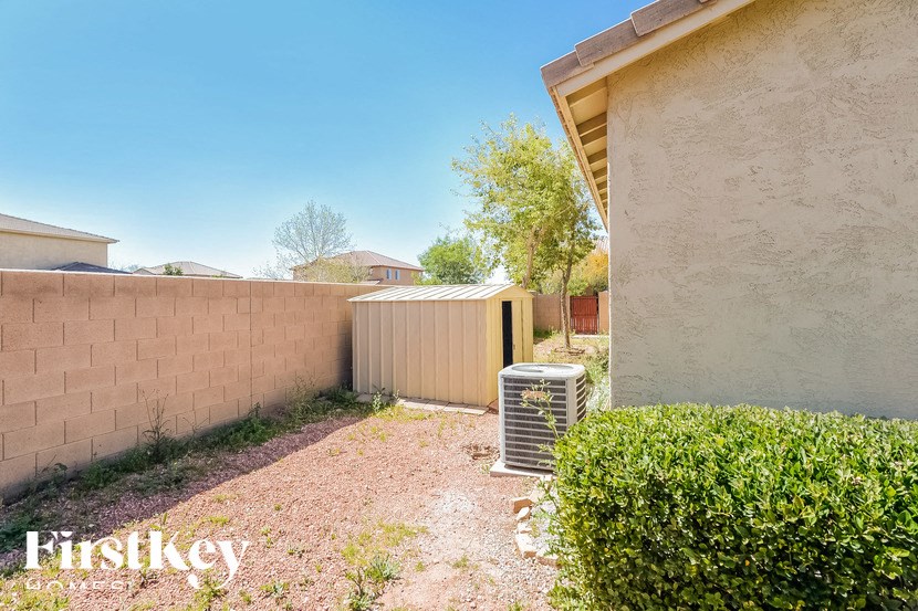 A backyard with a wall, a bush, and a fence.