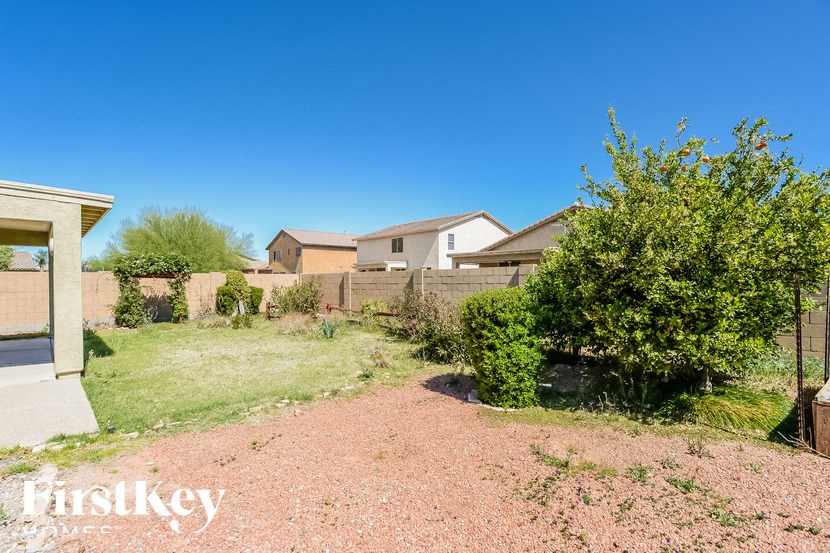 A house with a gravel driveway and a green bush in front.