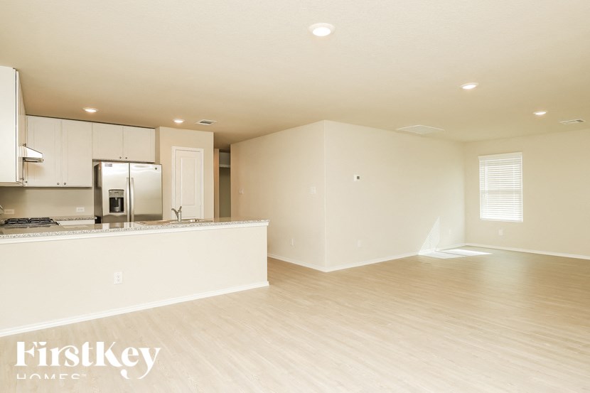 A spacious kitchen with white cabinets and a wooden floor.