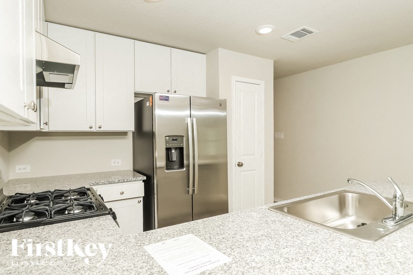 A kitchen with a stove, refrigerator, and sink.