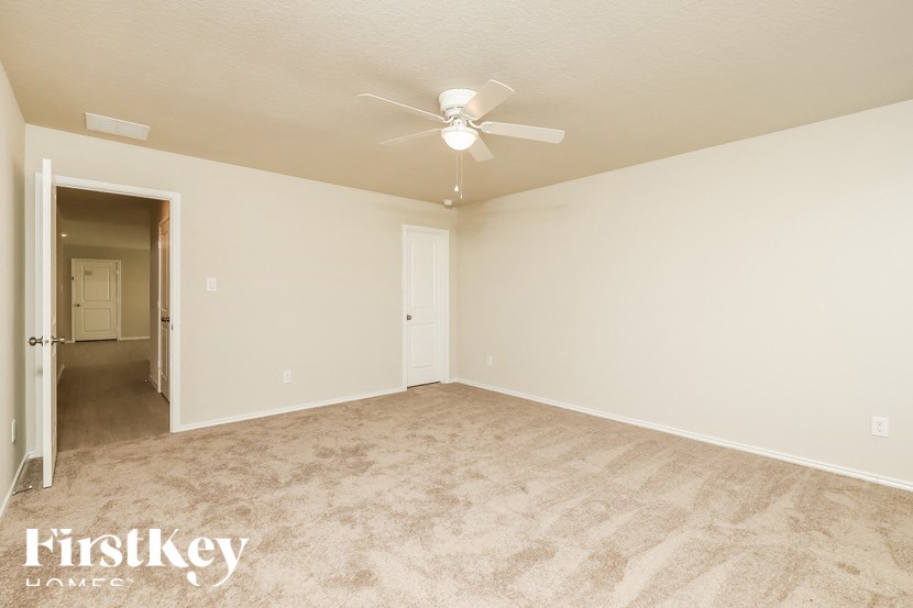 A spacious room with a ceiling fan and beige carpeting.