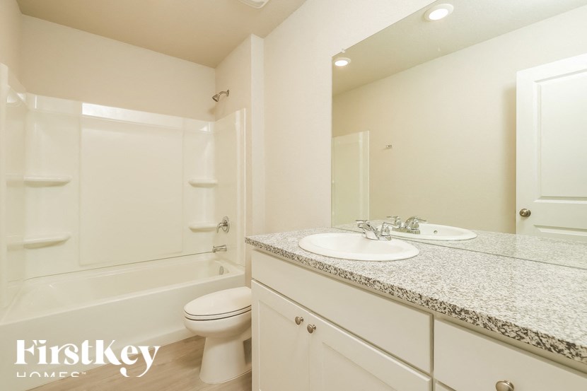 A white bathroom with a marble countertop and a toilet.