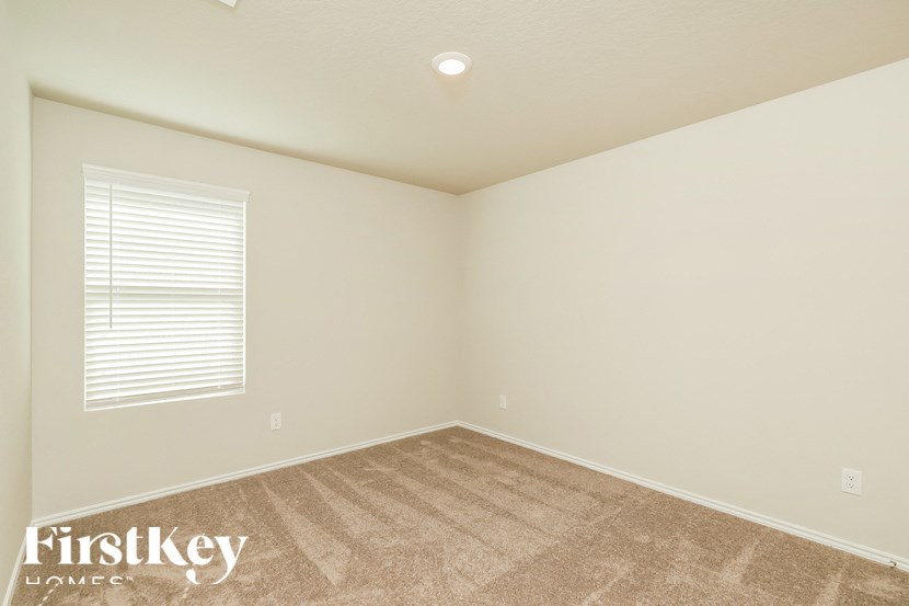 A room with a carpeted floor and a window with blinds.