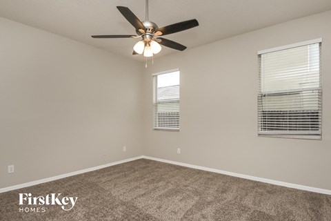 the spacious living room with carpeting and a ceiling fan