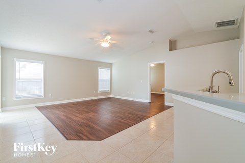 A spacious room with a wooden floor and a kitchen area with a sink.