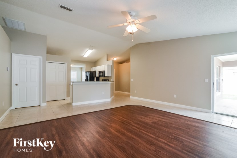 A spacious room with wooden flooring and a ceiling fan.