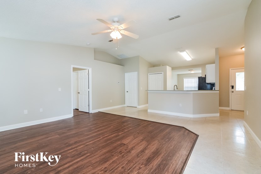 A spacious living room with a wooden floor and a ceiling fan.
