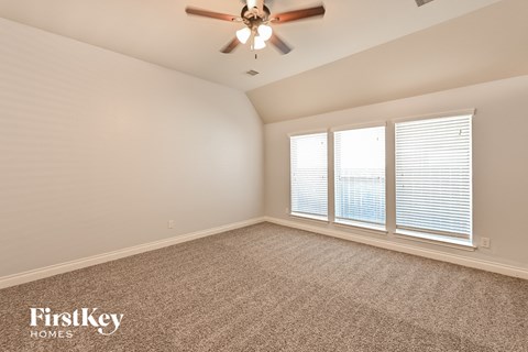 a living room with a ceiling fan and three windows