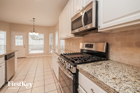 an updated kitchen with granite counter tops and a stove and microwave