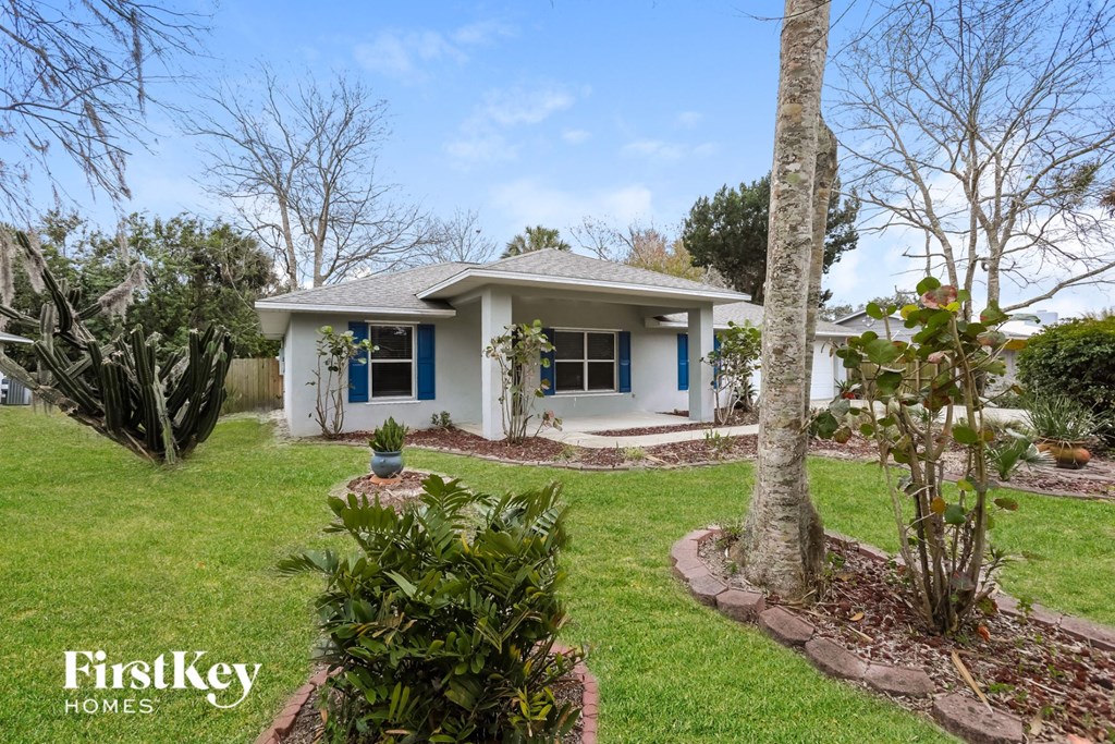a small white house with a yard and a tree