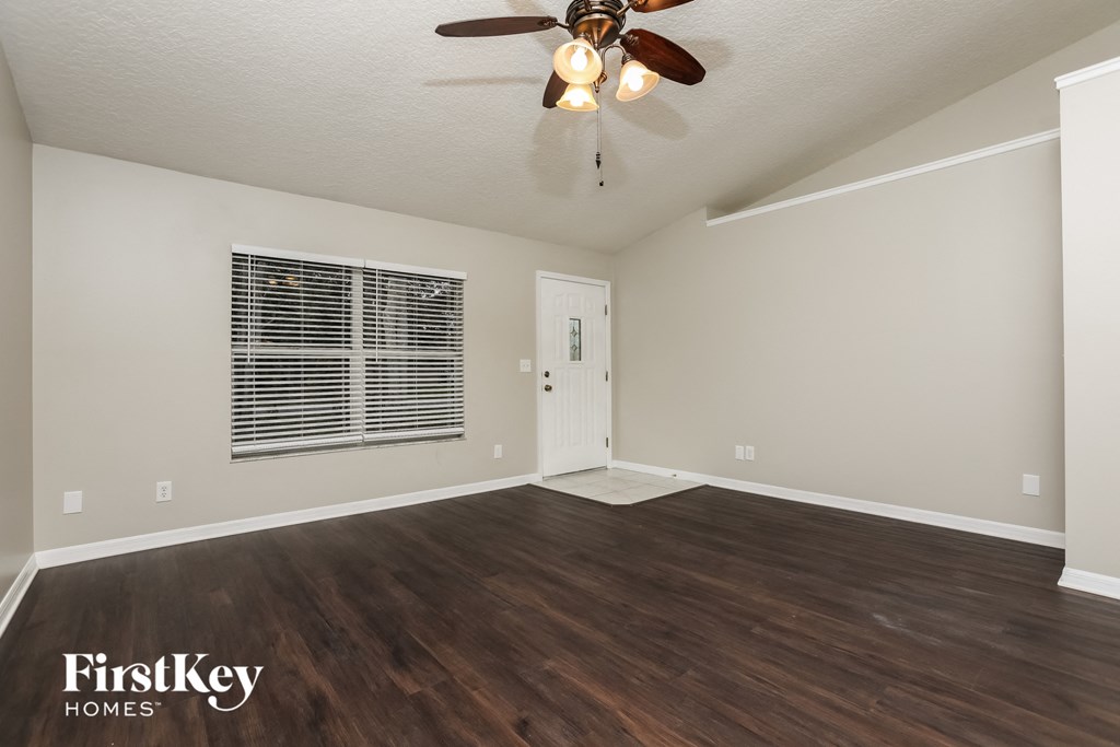 the living room of an empty house with a ceiling fan